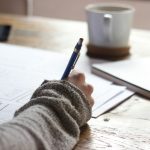 Home 7 person writing on brown wooden table near white ceramic mug