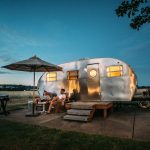 Home 8 man and woman sitting in front of RV trailer